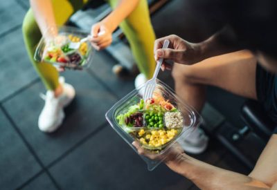 istockphoto-1423997728-612×612 Top view Asian man and woman healthy eating salad after exercise at fitness gym. Two athlete eating salad for health together. Selective focus on salad bowl on hand.